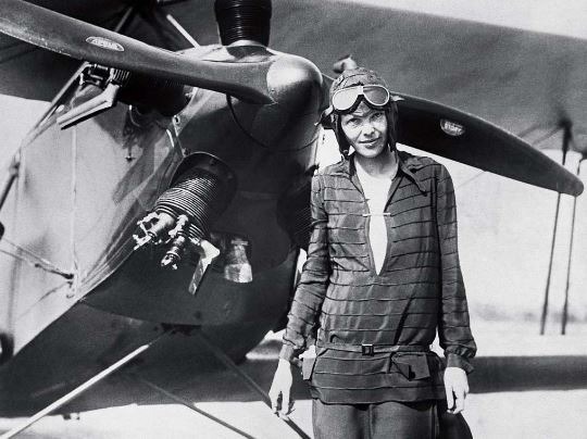 Amelia Earhart standing in front of a plane