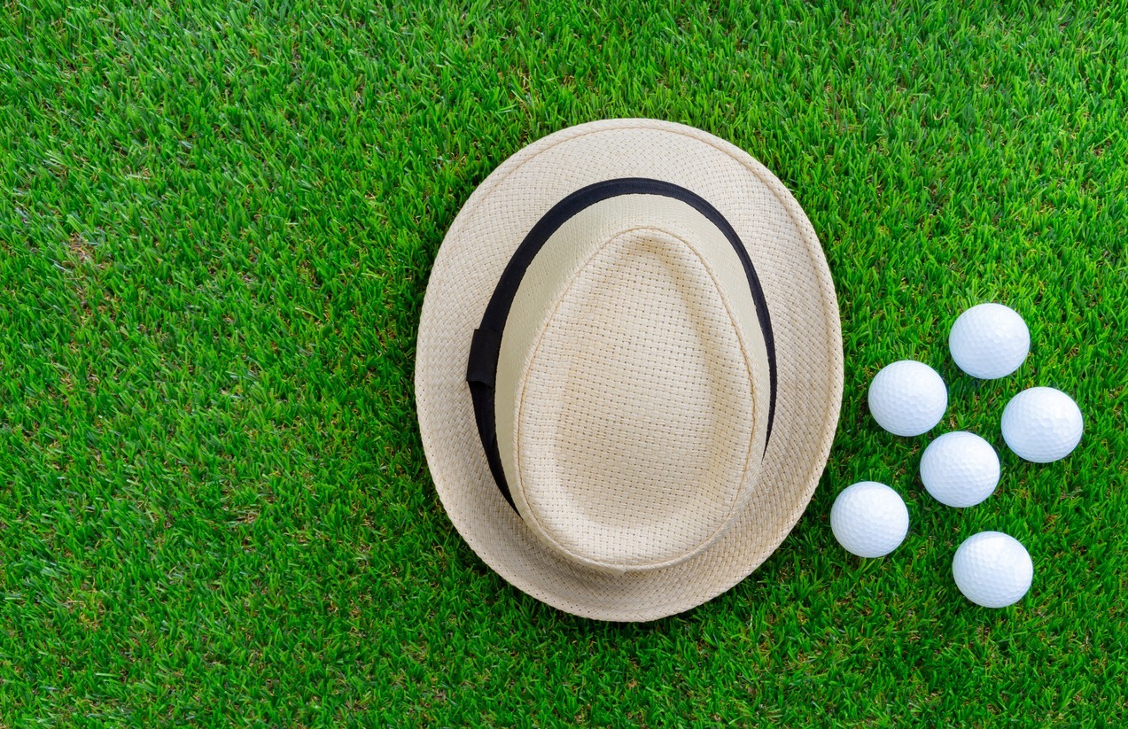 Panama-hat-golf-balls-flat-lay-on-green-glass