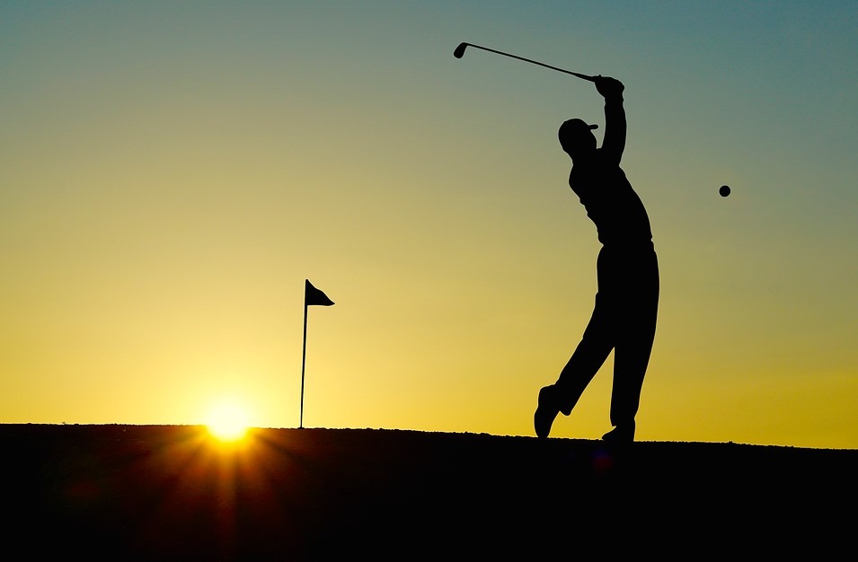 silhouette-of-a-man-hitting-a-golf-ball-setting-sun-pole-with-a-flag
