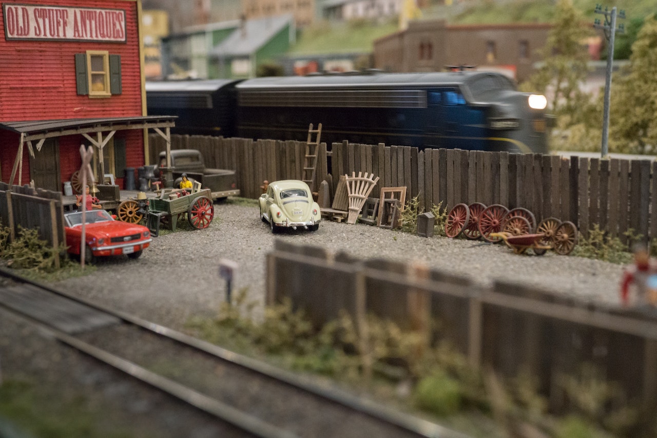 a miniature model train running beside an old house  