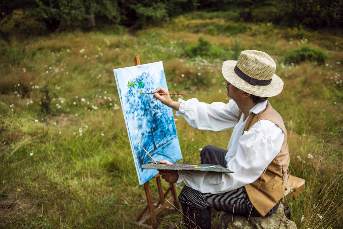 Photo of a Man Sitting while Painting