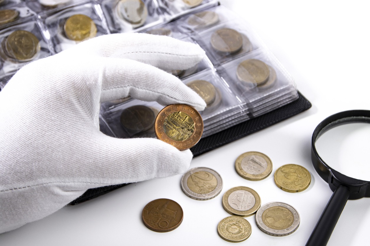 a collector wearing white gloves examining a coin