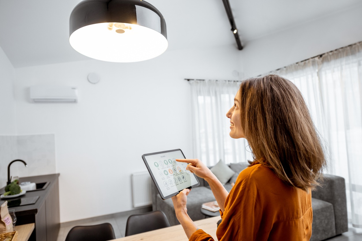 a woman controlling light with a digital tablet at home