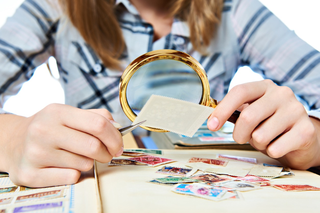 a woman with a magnifier looking closely at a stamp