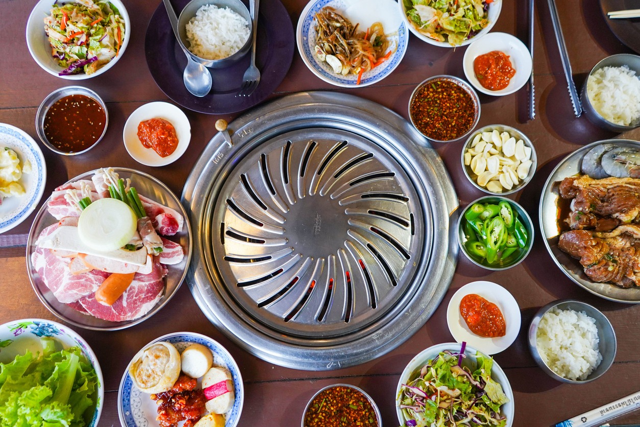 a Korean barbeque grill with meat and side dishes