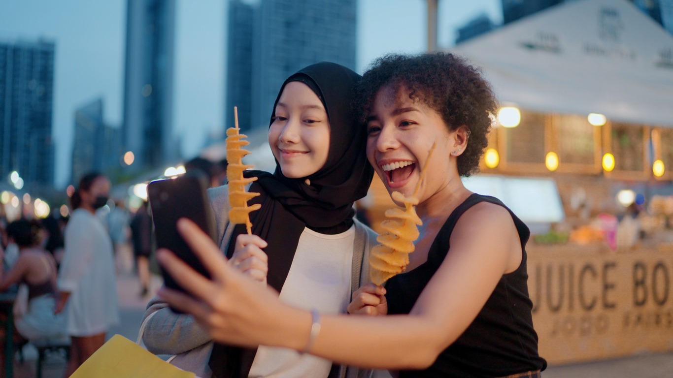 a couple of friends taking selfie with street food in Thailand