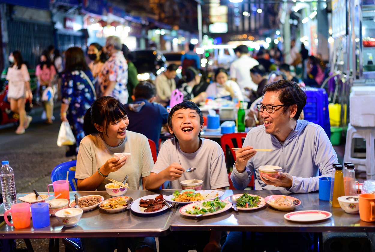 a family eating food on a street restaurant