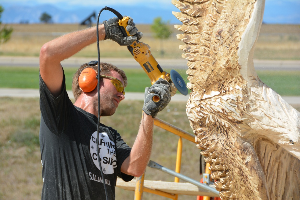 a man using a power tool to make a wooden sculpture