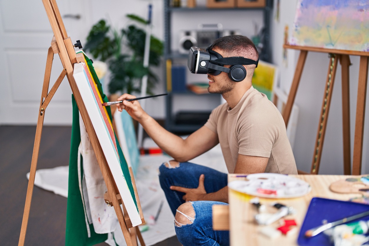 a man using virtual reality headsets as he paints on a real canvas