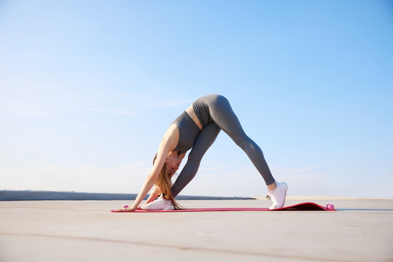 a woman doing a downward-facing dog position on a shore