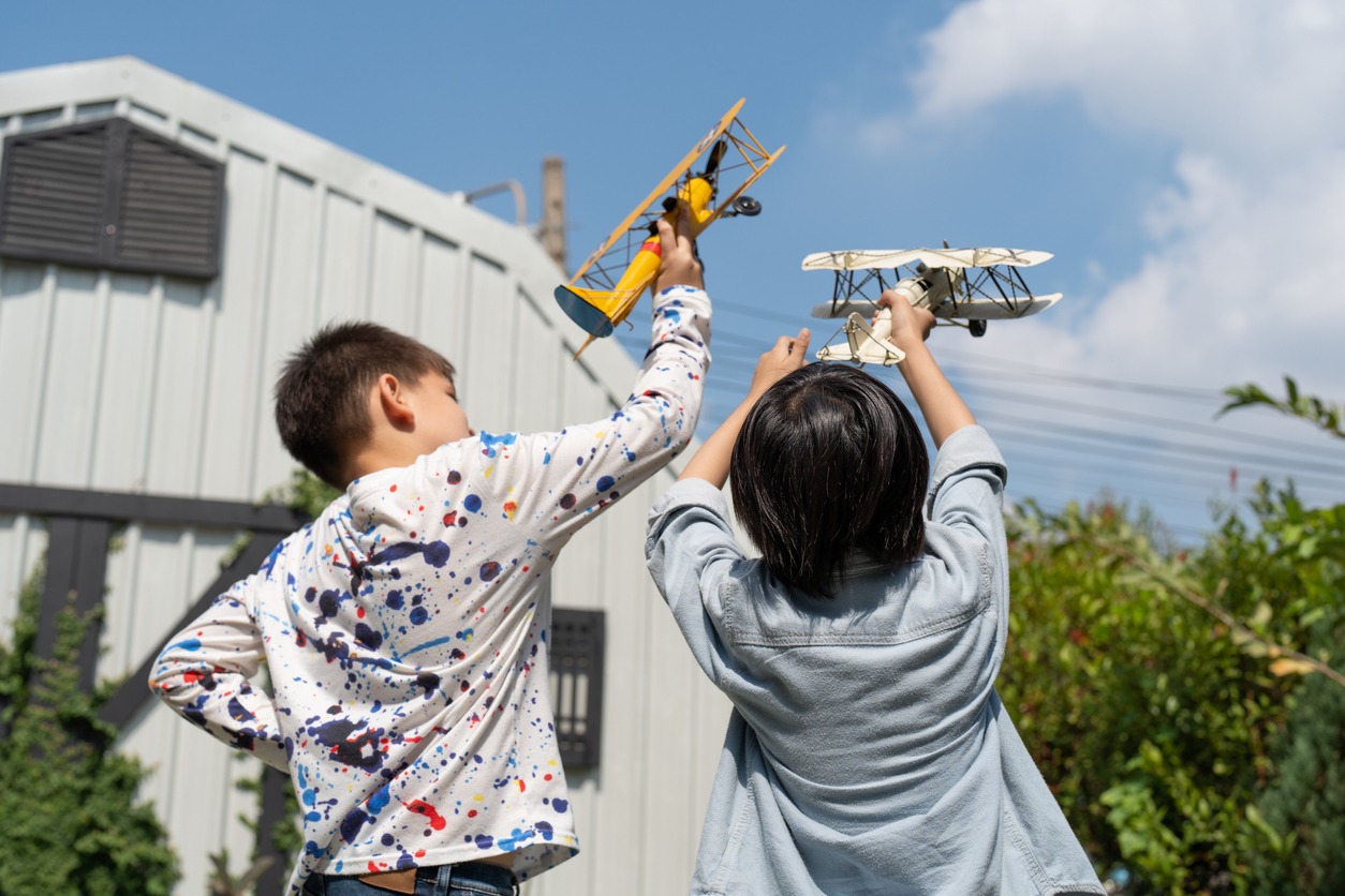 two boys playing toy airplane model at home