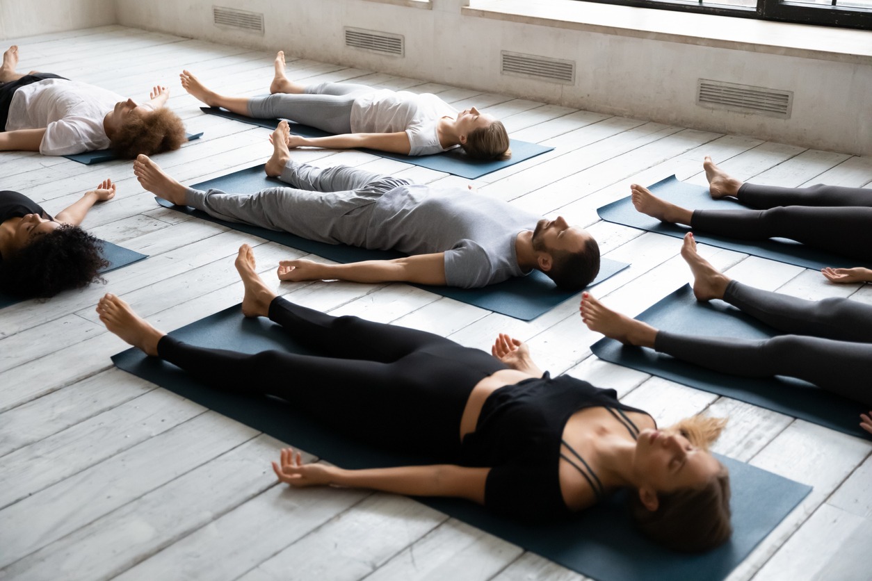 A group of people meditating in Savasana pose on the floor