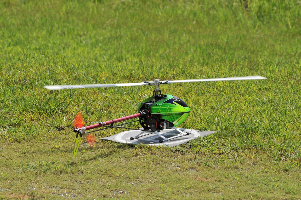 A neon green remote control helicopter flying outdoors