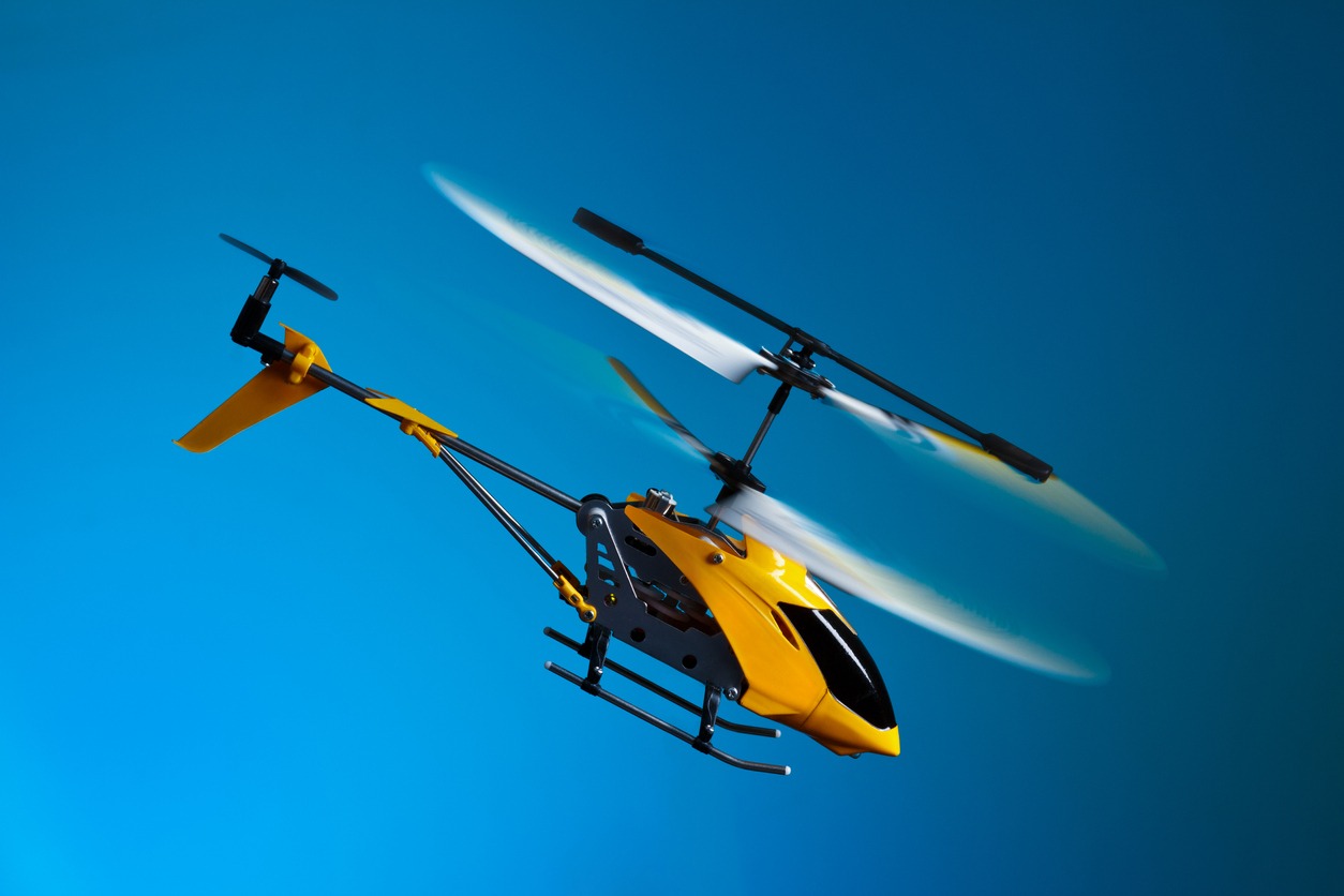 A yellow remote control helicopter with the blue sky in the background