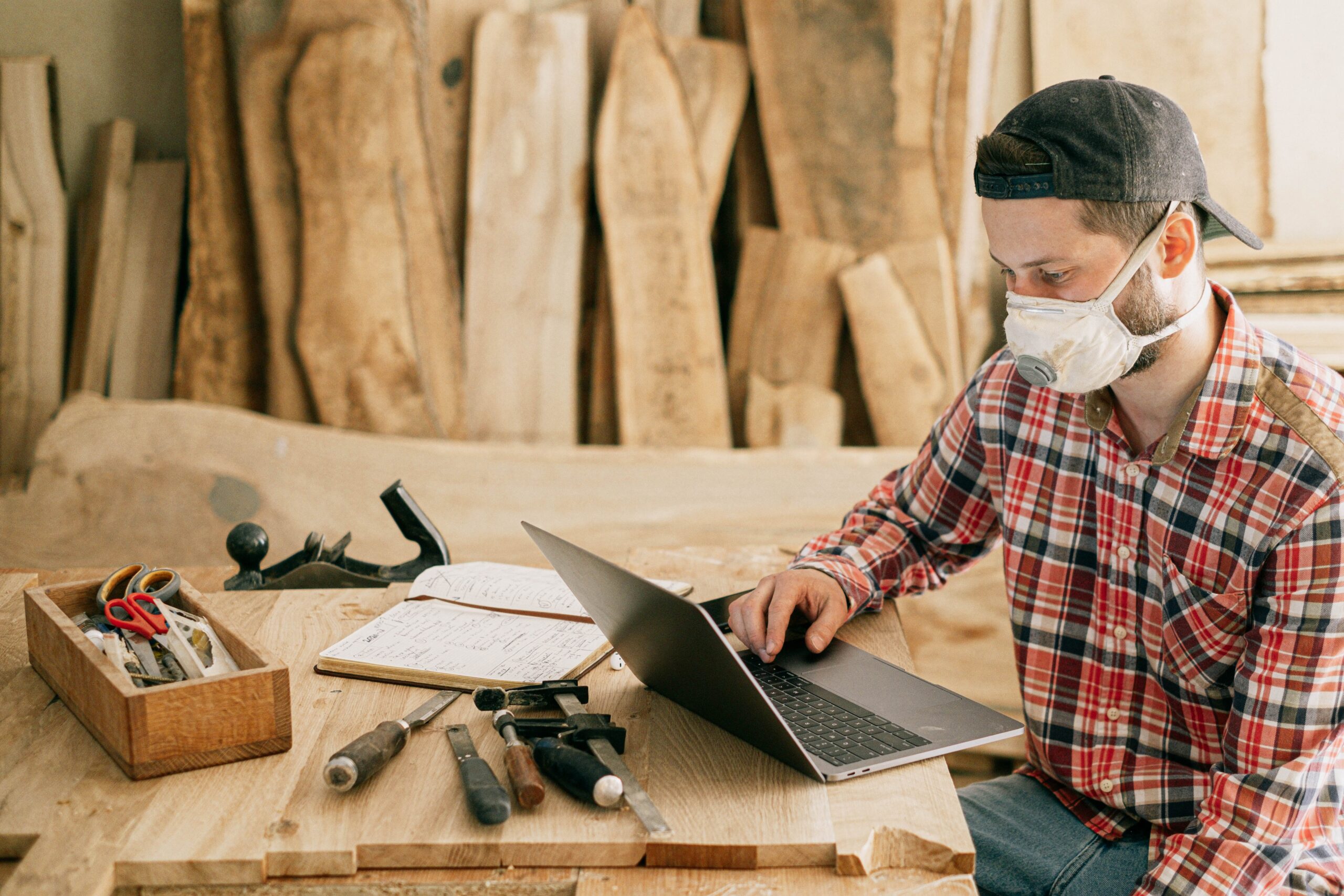 man-using-a-laptop-at-a-wood-workshop