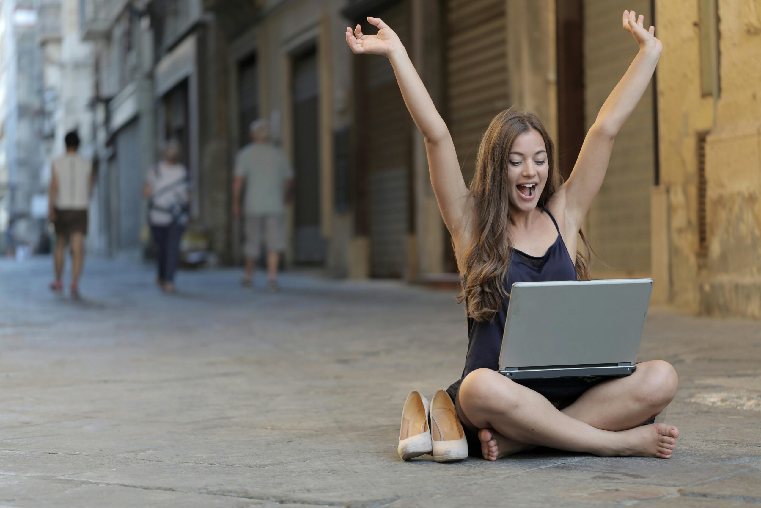 woman-raising-her-hands-up-while-sitting-on-floor-with-macbook-pro