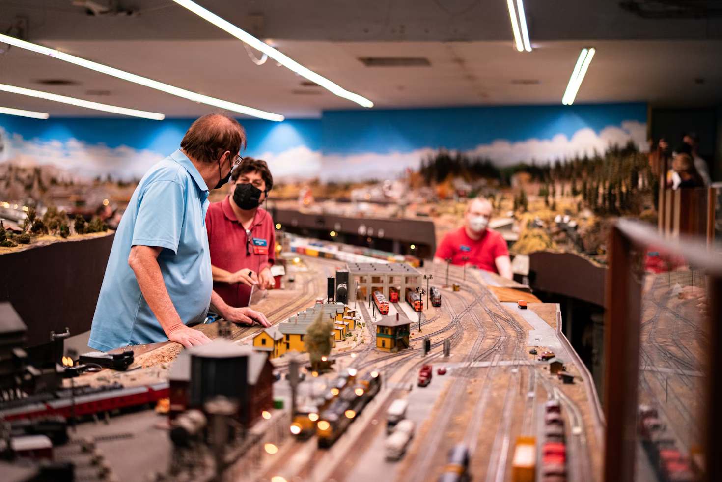 A couple of men standing next to a model train set