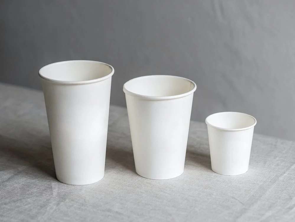 Three white disposable cups on white table