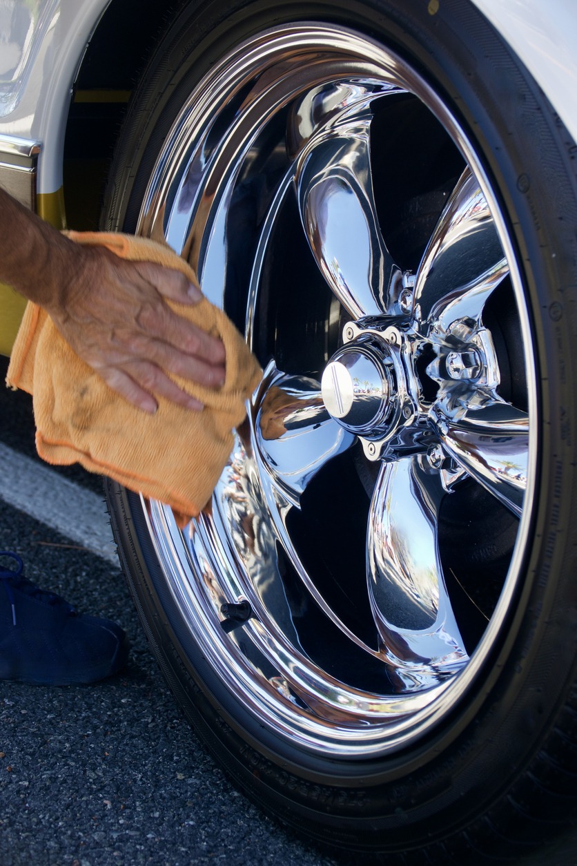 Closeup of man polishing the chrome wheel of the sports car