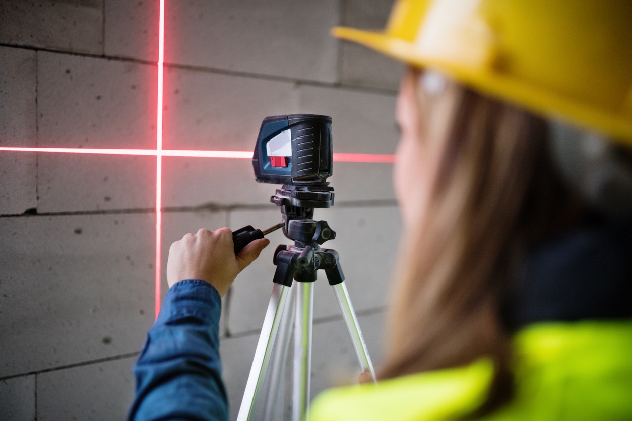 Young woman worker with laser on the building site